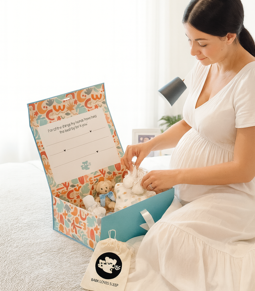 Expecting Mom opening a beautiful baby gift box with a teddy bear inside, sitting on a couch.